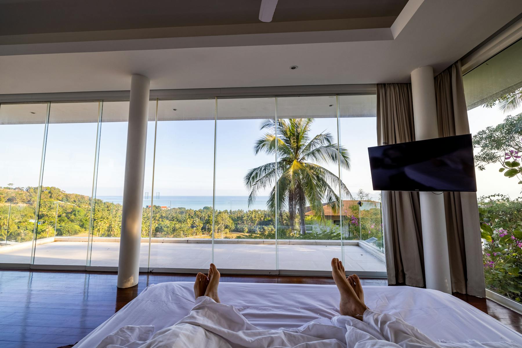 Bright Miami Beach bedroom with ocean view and palm trees outside the window