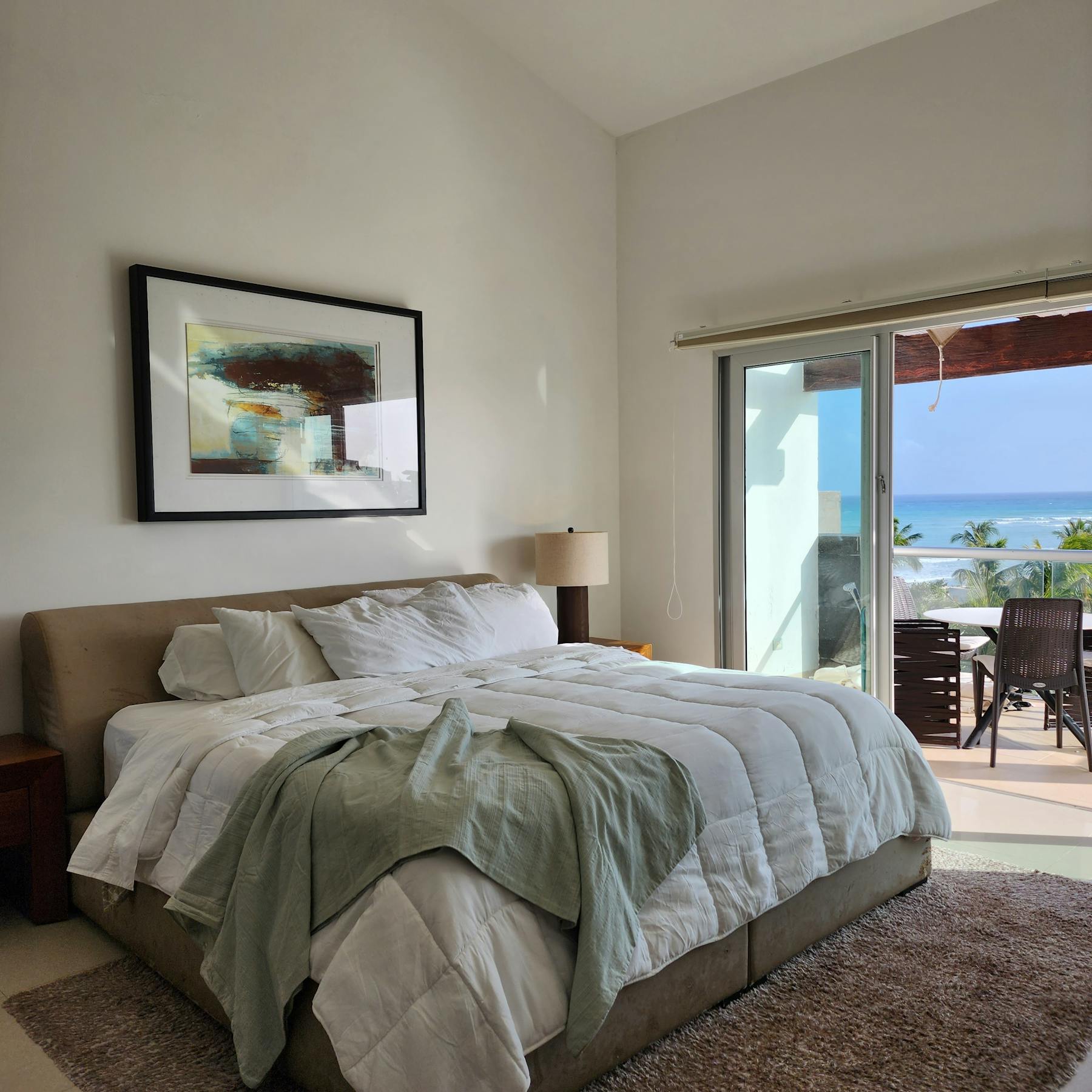 Modern Miami condo bedroom opening onto an ocean-view terrace with tropical decor